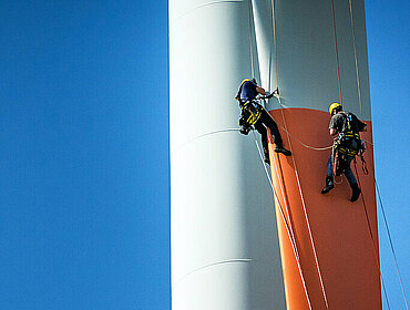 Inspektionsingenieure seilen sich am Rotorblatt einer Windkraftanlage ab