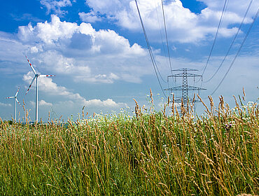 Strommast und Windräder in der Landschaft