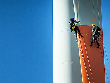 Inspektionsingenieure seilen sich am Rotorblatt einer Windkraftanlage ab