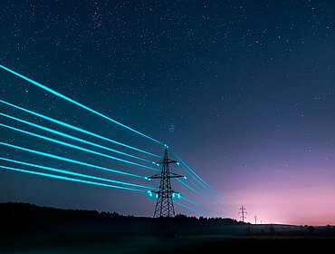 Strommasten mit glühende Kabel in einer Nachtlandschaft
