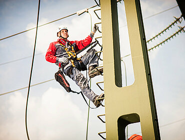Techniker klettert auf einem Strommast