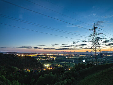 High power electricity pylon above a city skyline