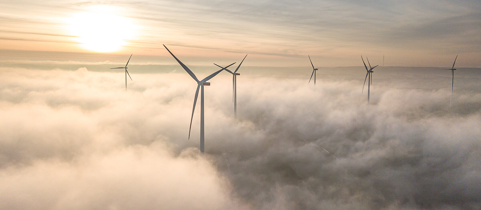 Windräder ragen über den Wolken
